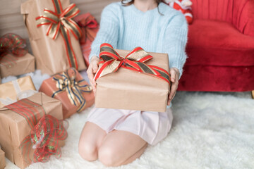 Caucasian woman in light blue sweater holding christmas gift box in in wrapping paper with bow. Christmas holiday. Copy space. High quality photo