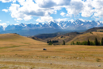 black car driving on dirt road in Kurai area with North Chuisky Ridge on background.