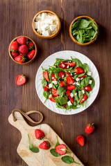 Top view of spinach salad with strawberry and goat cheese