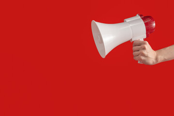 Megaphone in woman hands on a red background.