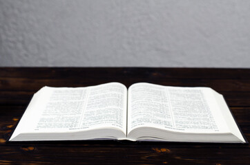 Fototapeta na wymiar Open Bible, on a wooden table. Light from the book. Desktop.