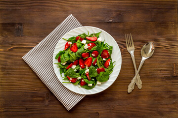 Top view of spinach salad with strawberry and goat cheese