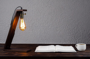 Open Bible book, on a wooden table. Desk lamp. Workplace. Desktop.