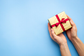 Female hands holding golden gift box - present background