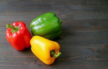 Tricolor fresh ripe bell peppers on black wooden background 
