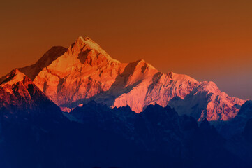 Fototapeta na wymiar Beautiful first light from sunrise on Mount Kanchenjugha, Himalayan mountain range, Sikkim, India. Orange tint on the mountains at dawn