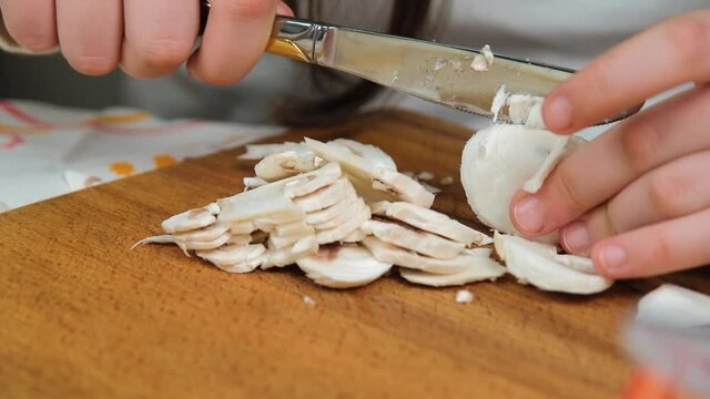 Children cooks pizza. Prepering ingredients for pizza. Children cut mushrooms and tomatoes on the board. Preparing tasty pizza together. At home, in kitchen. Mozzarella-mushroom pizza recipe, close up