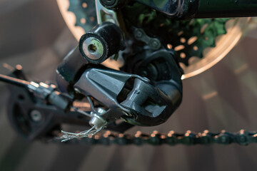 The rear derailleur of a mountain bike is a close-up on a black background. Mountain bike repair in the workshop. Dirty mountain bike after the competition.