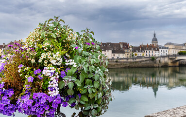Fototapeta na wymiar Chalon-sur-Saone, France, a flower pot in foreground, blurred church tower and part of the bridge in the background