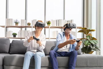 senior couple playing game and having fun together with virtual reality headset on the sofa