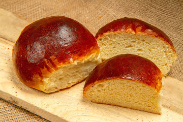 A sweet bun of round shape against the background of wood and burlap.