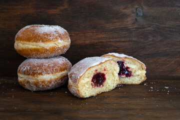 Berliner donuts or Krapfen filled with red jam, traditional sweet pastry for carnival and New Year, dark brown rustic wood, copy space, selected focus - obrazy, fototapety, plakaty