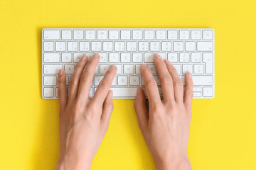 Top view on female elegant hands on a computer keyboard isolated yellow background and clipping. Assistance service respond on e mail. - obrazy, fototapety, plakaty