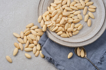 White peeled or blanched almonds. Healthy almond in a plate with napkin on gray granite background. Shallow depth of field