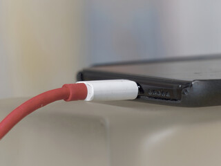 Close-up photo of a smartphone plugged into a charger with a blurry background