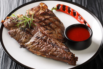 Grilled BBQ T-Bone Steak with Fresh Rosemary close up in the plate on the black table. Horizontal