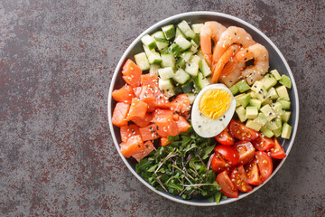 Organic breakfast of salmon, shrimps, eggs and fresh vegetables close-up in a plate on a concrete table. horizontal top view from above