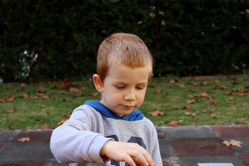 The blond boy looks at the toys with concentration. Four year old pensive boy 