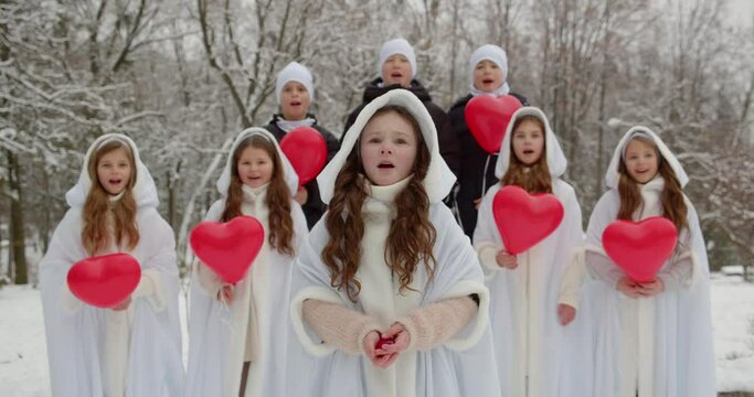 A group of children sing a song in the park in winter