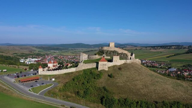 Drone shot fly away of Rupea fortified citadel in Brasov, Romania. Classic Transylvania medieval fortress, aerial view. 