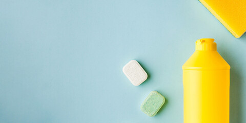 Liquid dishwashing liquid, dishwasher tablets on a blue background. Means for washing dishes. Copy space. Flatlay.