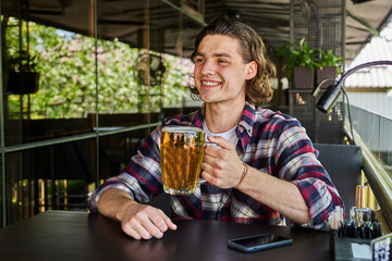 Smiling man drinking beer on summer terrace cafe