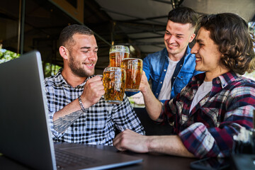 Three happy men watching football in a pub and drinking beer.