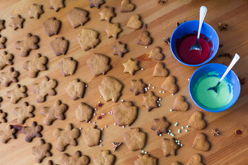 The cooking process: baked christmas or new year ginger cookies in shape of little men, houses, stars and hearts are waiting for painting with icing sugar