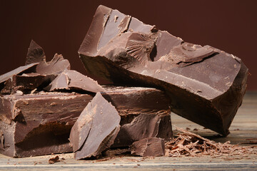 Composition of Bars and Pieces Dark Chocolate. Chipped Dark Chocolate Stack  With Chocolate Chips on a Wooden Kitchen Board. Shallow depth of field