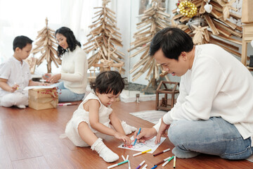 Parents and children drawing pictures at home for Christmas celebration