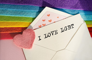 An open envelope with the textI I LOVE LGBT, on a pink and blue background with a decor of felt hearts and a flower. Flat lay, top view. LGBT concept.