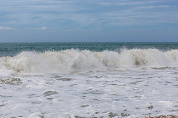 Asia. Sri Lanka. Waves beat against the seashore on the sandy beach of Ahungalla against the blue sky.