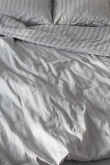 gray linens in sunlight on  bed in  bedroom