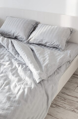 Fototapeta na wymiar gray linens in sunlight on bed in bedroom