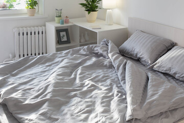 gray linens in sunlight on  bed in  bedroom