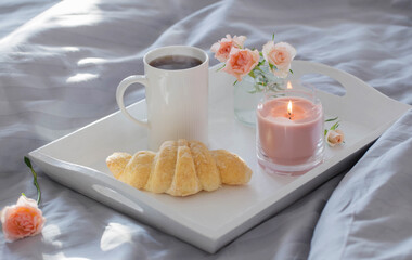 cup of coffee with croissant  and pink roses on bed in  bedroom