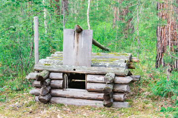 Ancient trap for animals made of logs in a summer forest. Life of prehistoric tribes