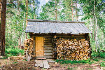 A lonely old house of the forester and a pile of firewood nearby in a forest glade in the Siberian taiga