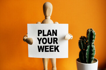 The wooden man holds a white sign with the text PLAN YOUR WEEK in his hands. The content of the...