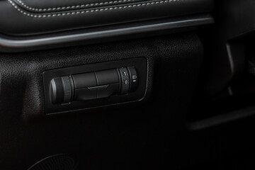 Naklejka premium Headlights corrector adjustment buttons. Сlose up view of the modern car black interior.