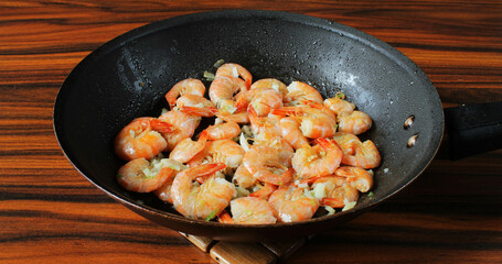 Brazilian seafood. Portion of shrimp in the frying pan on the wooden table.