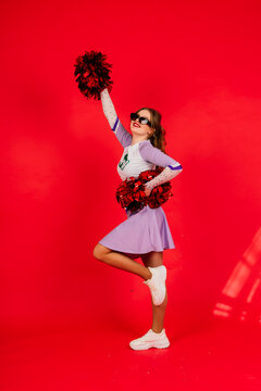 Young lady cheerleader posing in the studio, isolated on red and blue