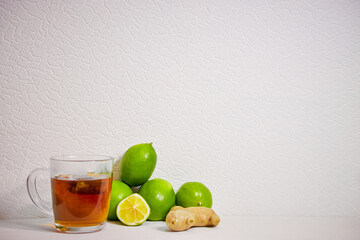 cup with tea , ginger and lime on a white background
