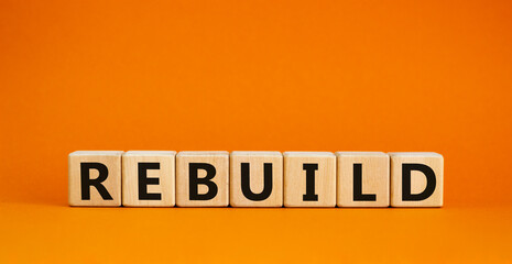Rebuild and build symbol. The concept word Rebuild on wooden cubes. Beautiful orange table, orange...
