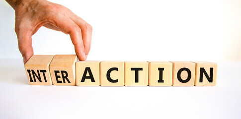 Action or interaction symbol. Businessman turns wooden cubes and changes the word action to interaction. Beautiful white table white background, copy space. Business and action or interaction concept.