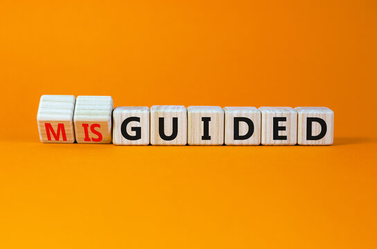 Guided or misguided symbol. Turned wooden cubes and changed the word misguided to guided. Beautiful orange table, orange background, copy space. Business and guided or misguided concept.