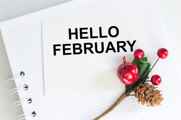 hello february greeting card, text on a white card with a notepad on the table