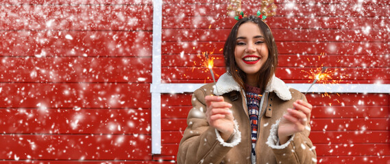 Smiling woman with Christmas sparklers at fair on snowy day