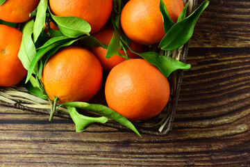 Zenith view, group of mandarins with their green leaves in a basket, on rustic boards. Copy space.