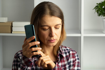 A blind woman uses a mobile phone while listening to the sound by clicking on the screen. The...